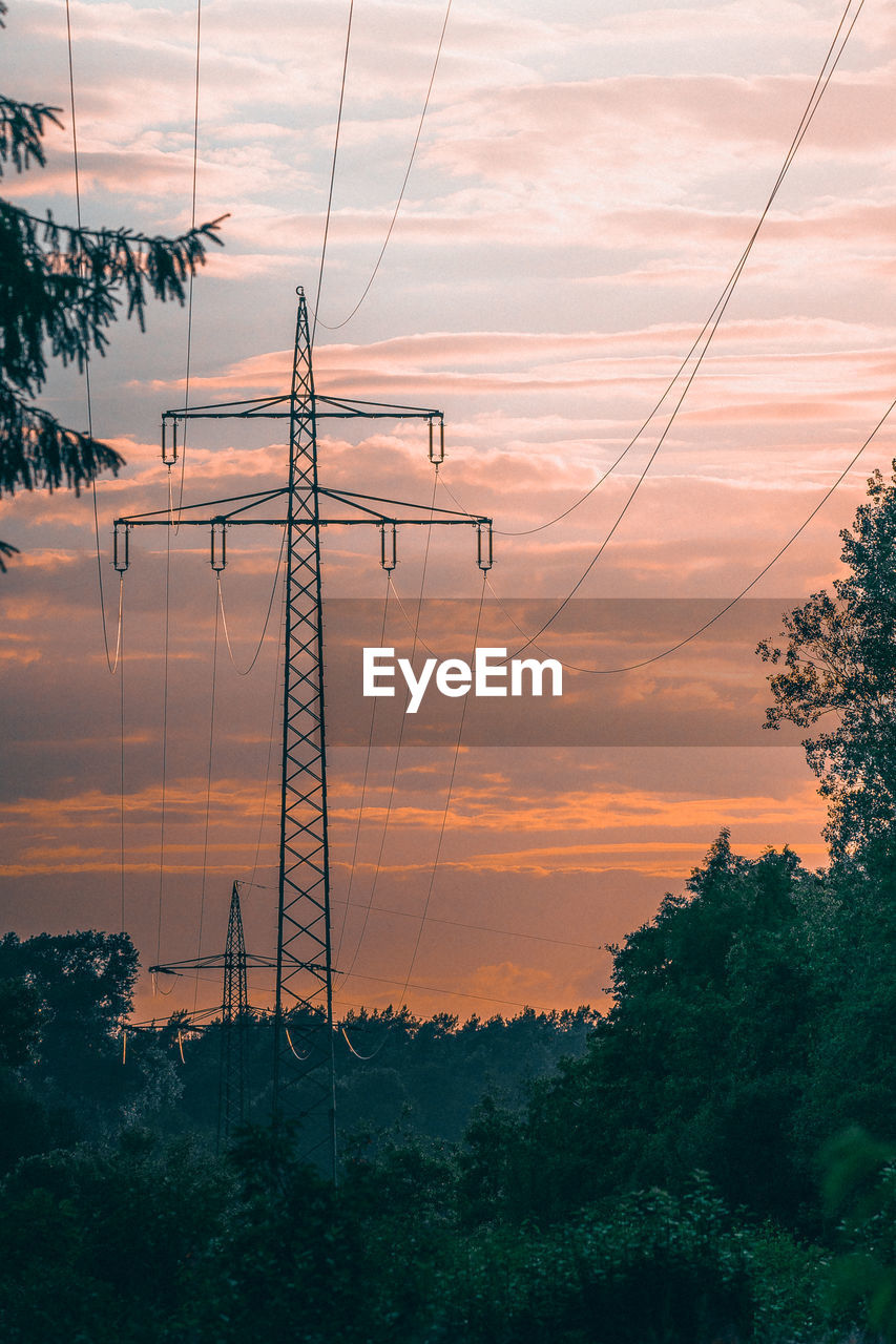 High voltage towers at sunset with trees