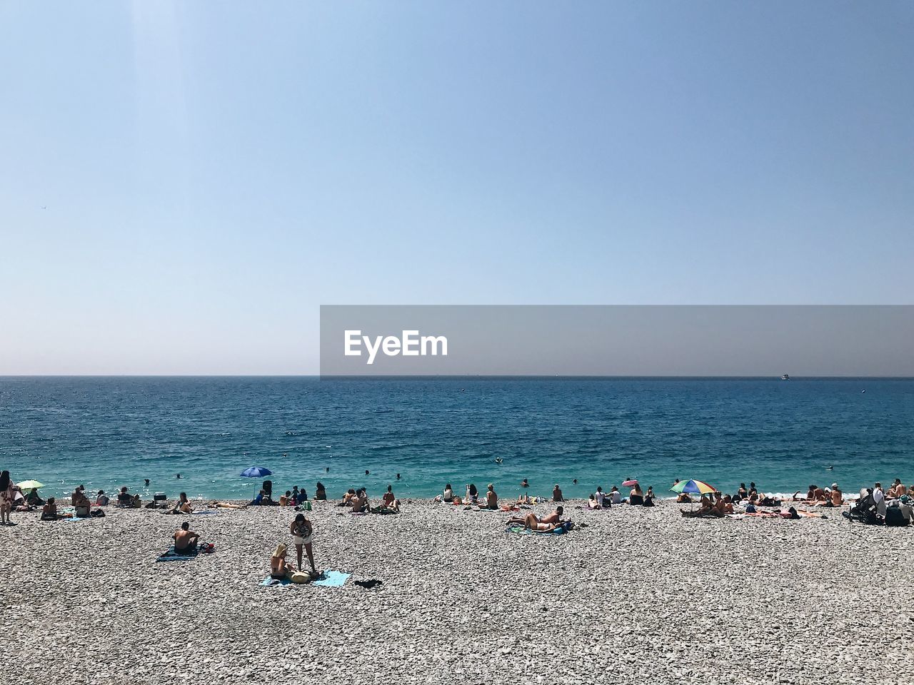 Group of people at beach against clear sky