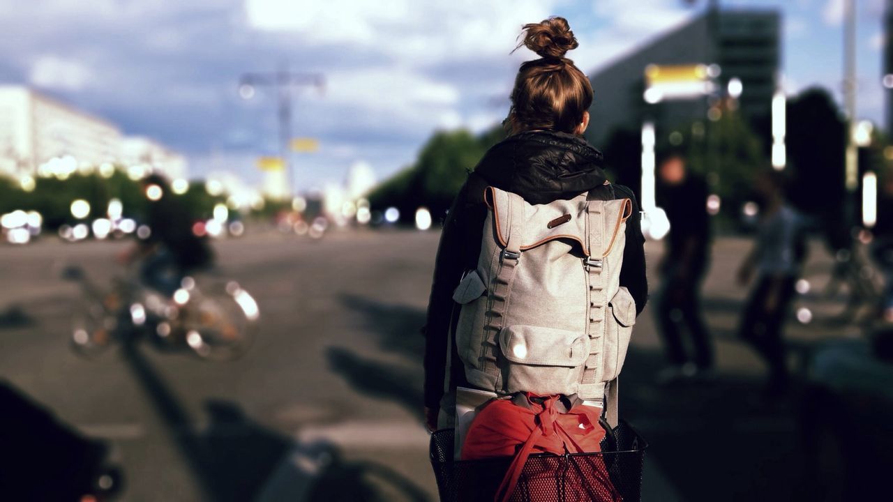 Rear view of woman with backpack walking on street