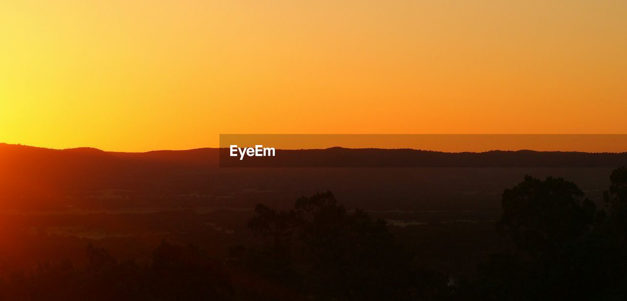 Scenic view of silhouette mountains against orange sky