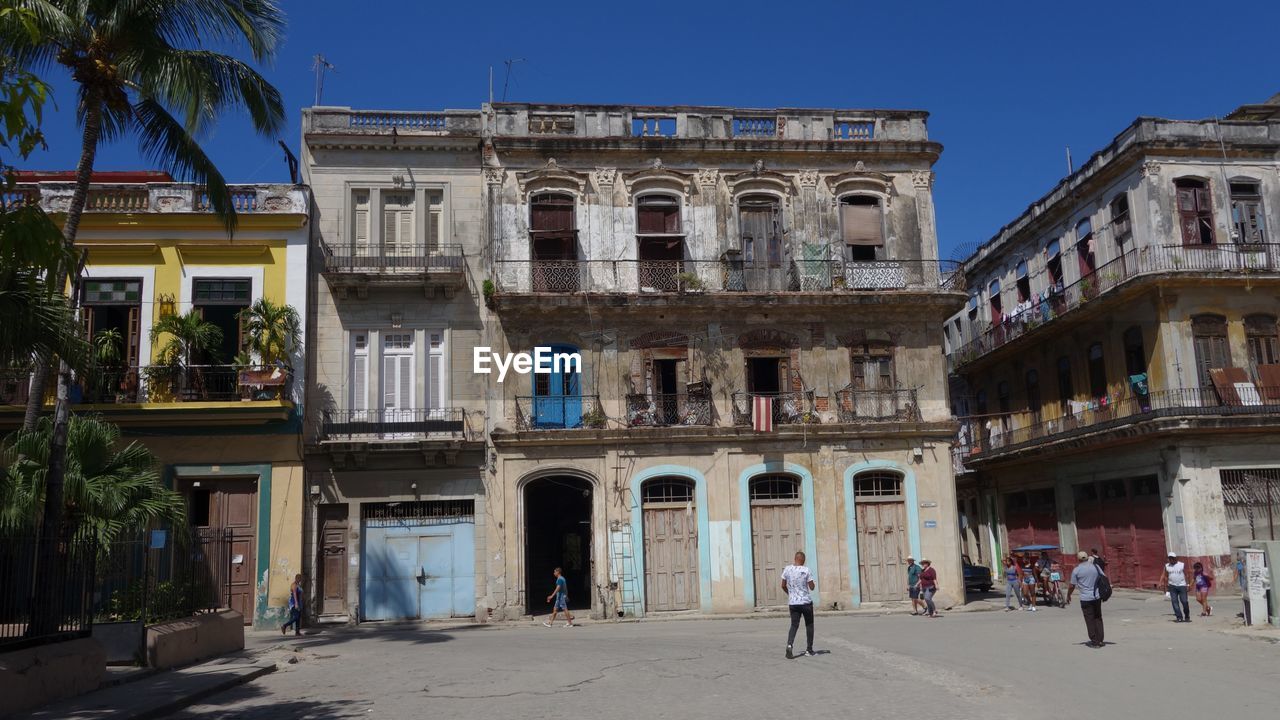 PEOPLE ON STREET BY BUILDING AGAINST SKY