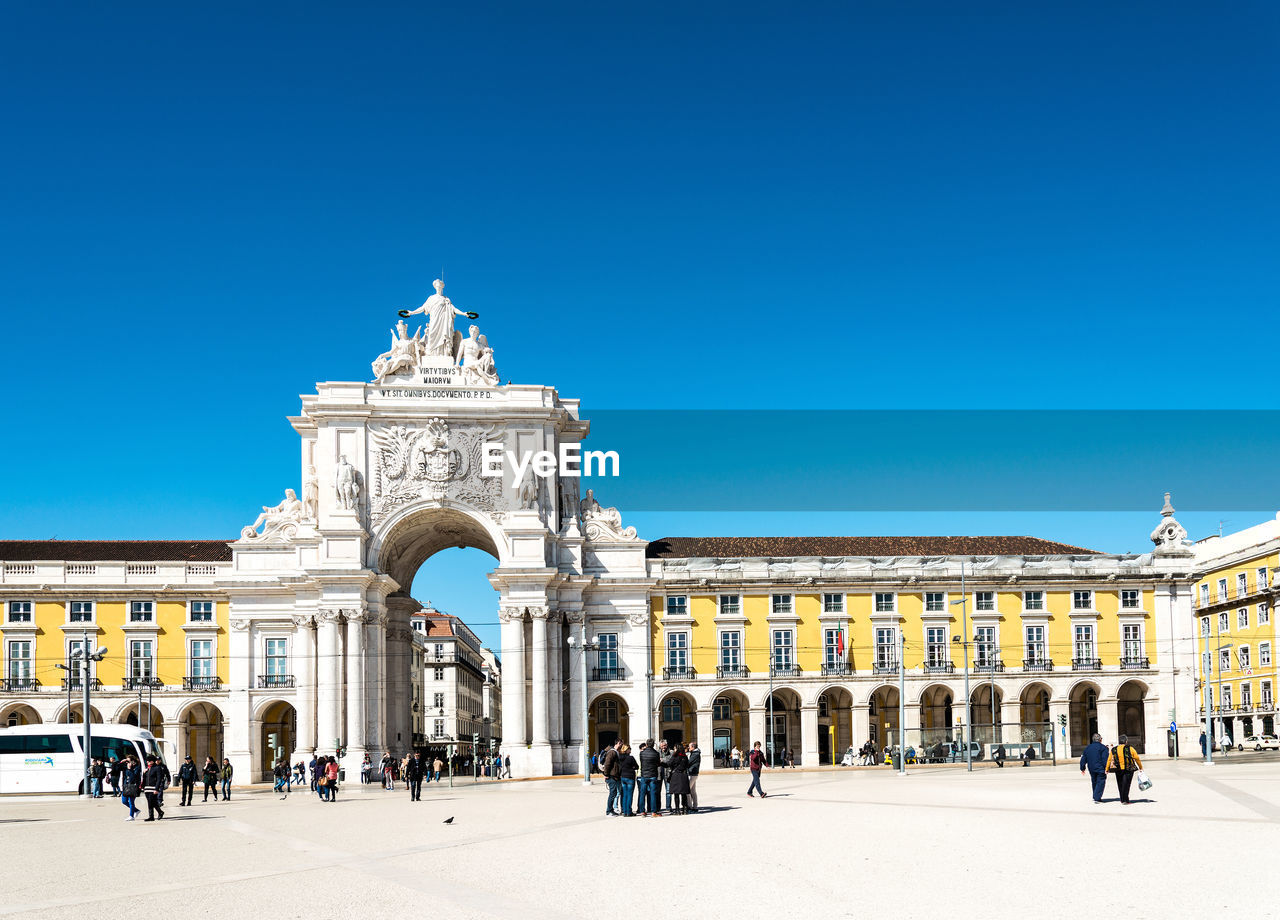 People by rua augusta against clear blue sky