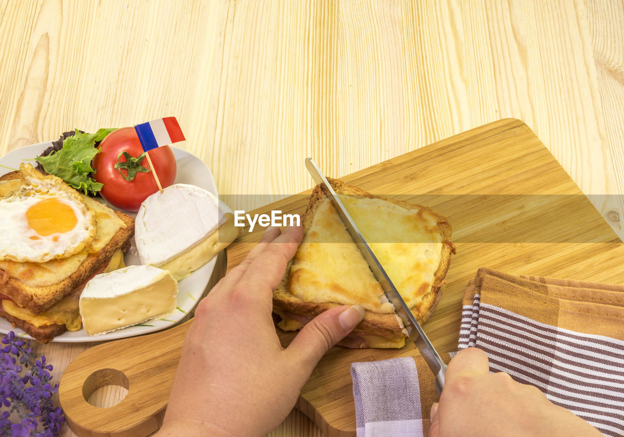 Woman cutting croque monsieur a traditional french sandwich