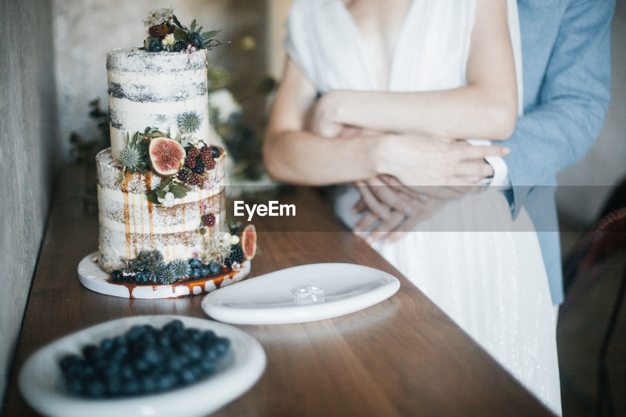 Midsection of couple with cake on table