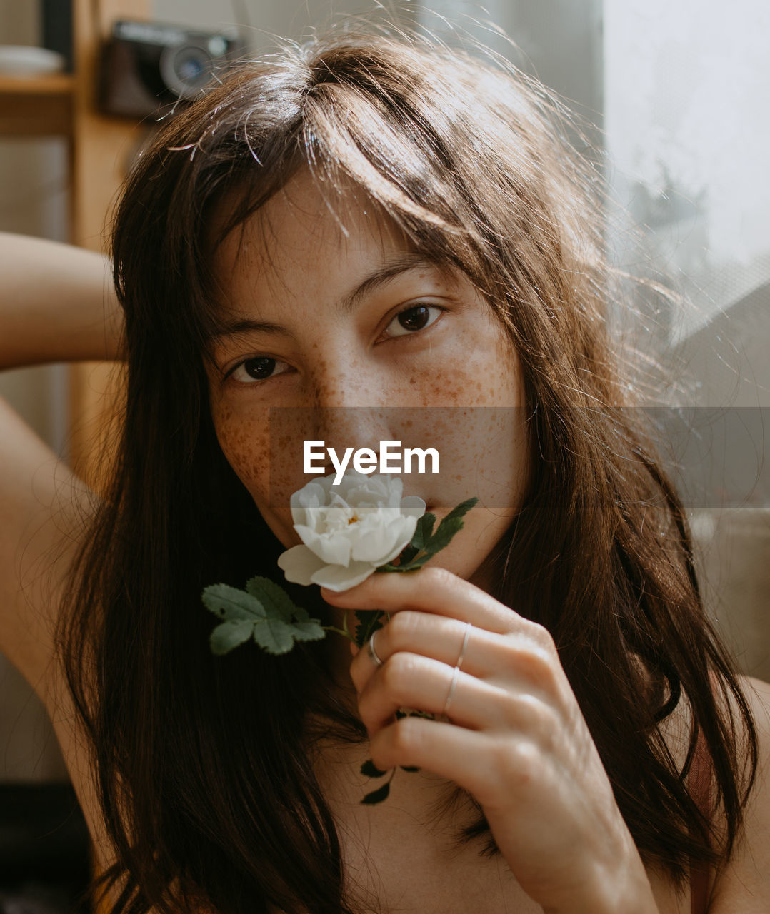 Portrait of young woman with dog rose at home