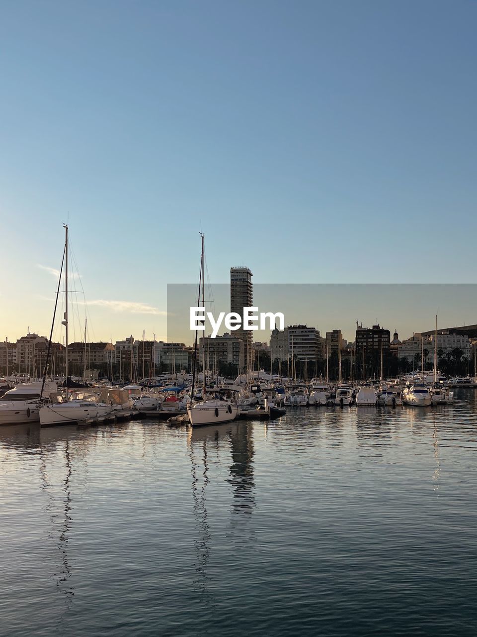 Boats in harbor against clear sky