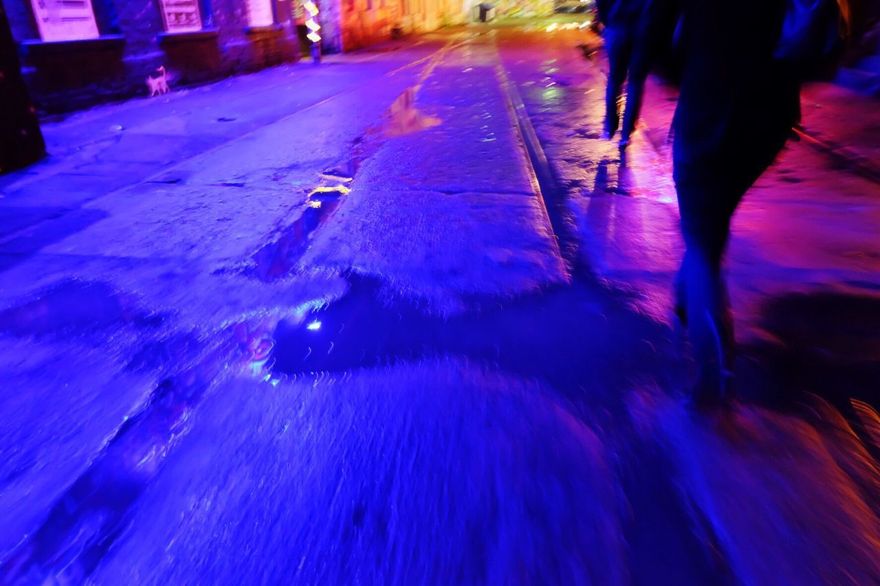 LOW SECTION OF WOMAN IN SNOW COVERED ILLUMINATED STREET