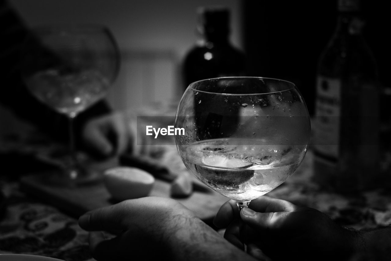 CLOSE-UP OF MAN HOLDING WINE IN GLASS