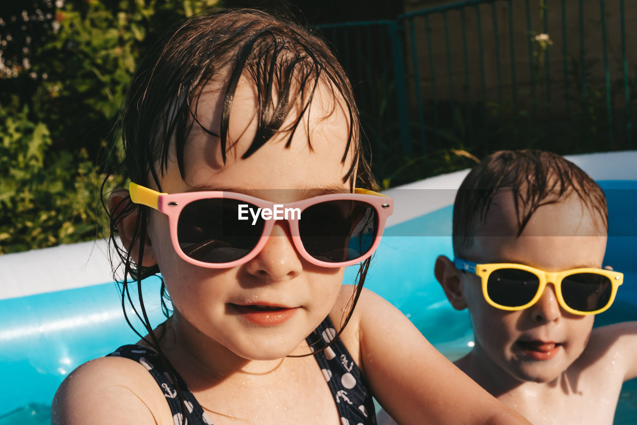 Portrait of happy children in sunglasses in swimming pool on summer hot day