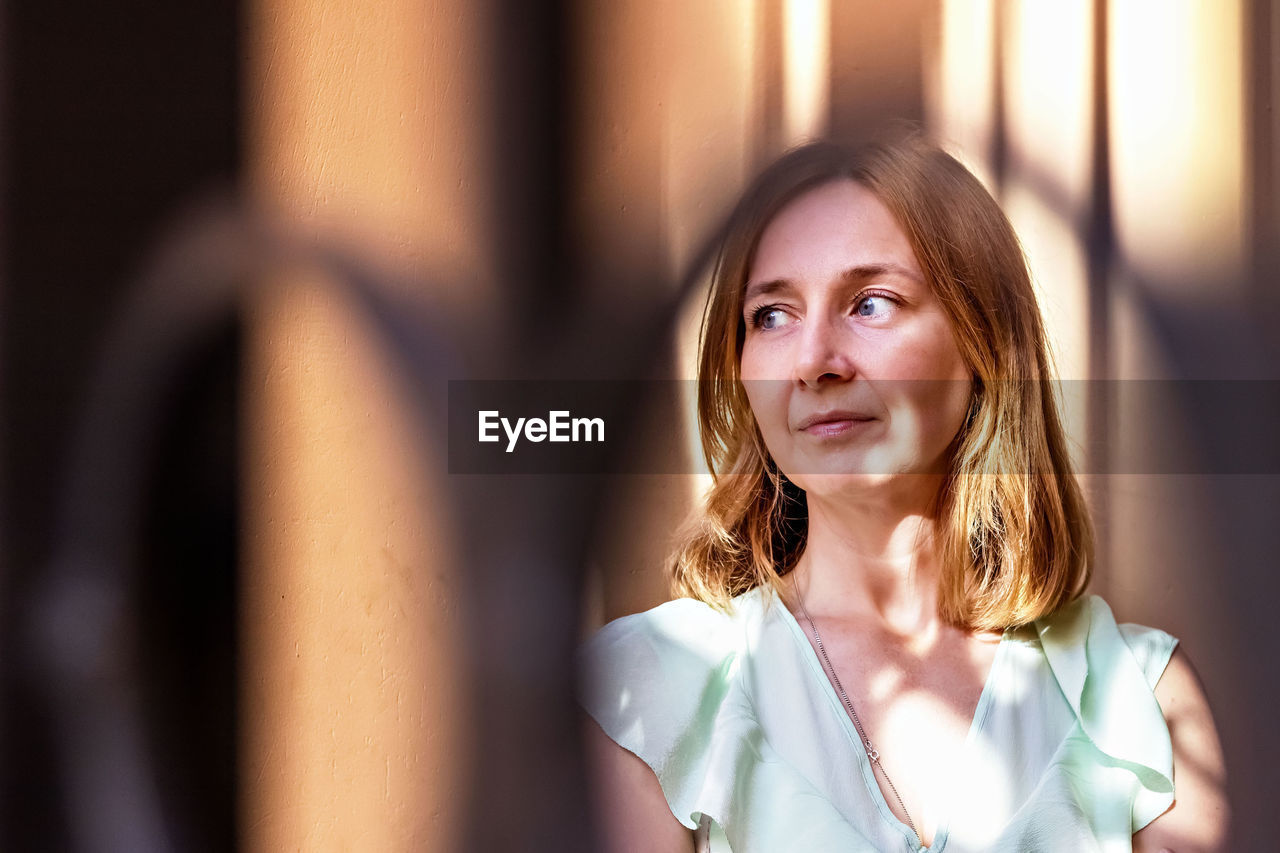 Portrait of a young woman with red hair through the lattice gate.