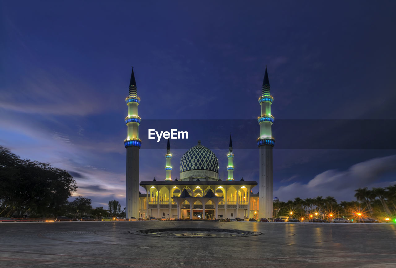 Illuminated mosque against sky at night