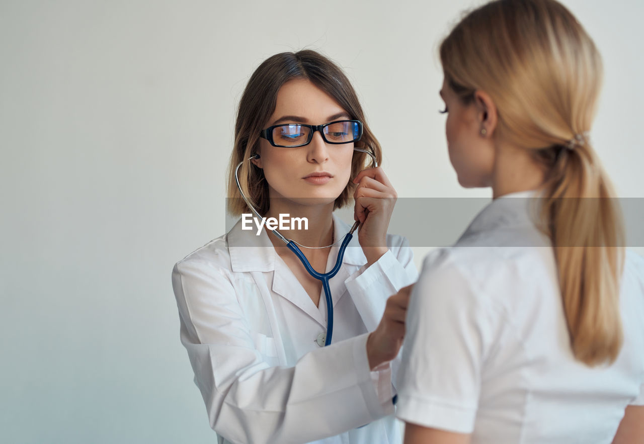 Doctor examining patient against white background