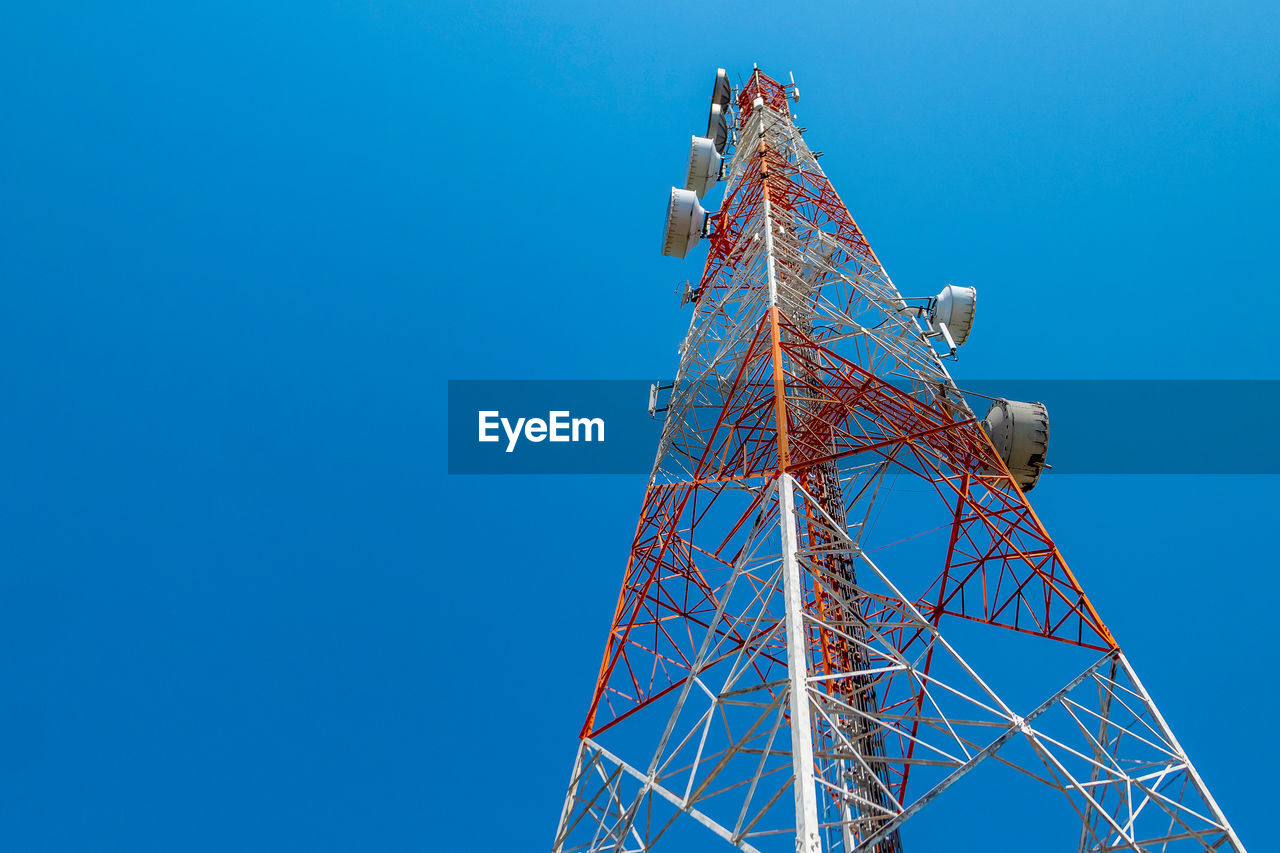 Low angle view of communications tower against clear blue sky