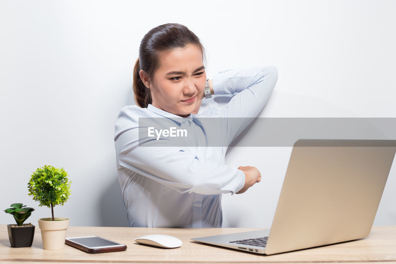 Businesswoman stretching while sitting at desk in office