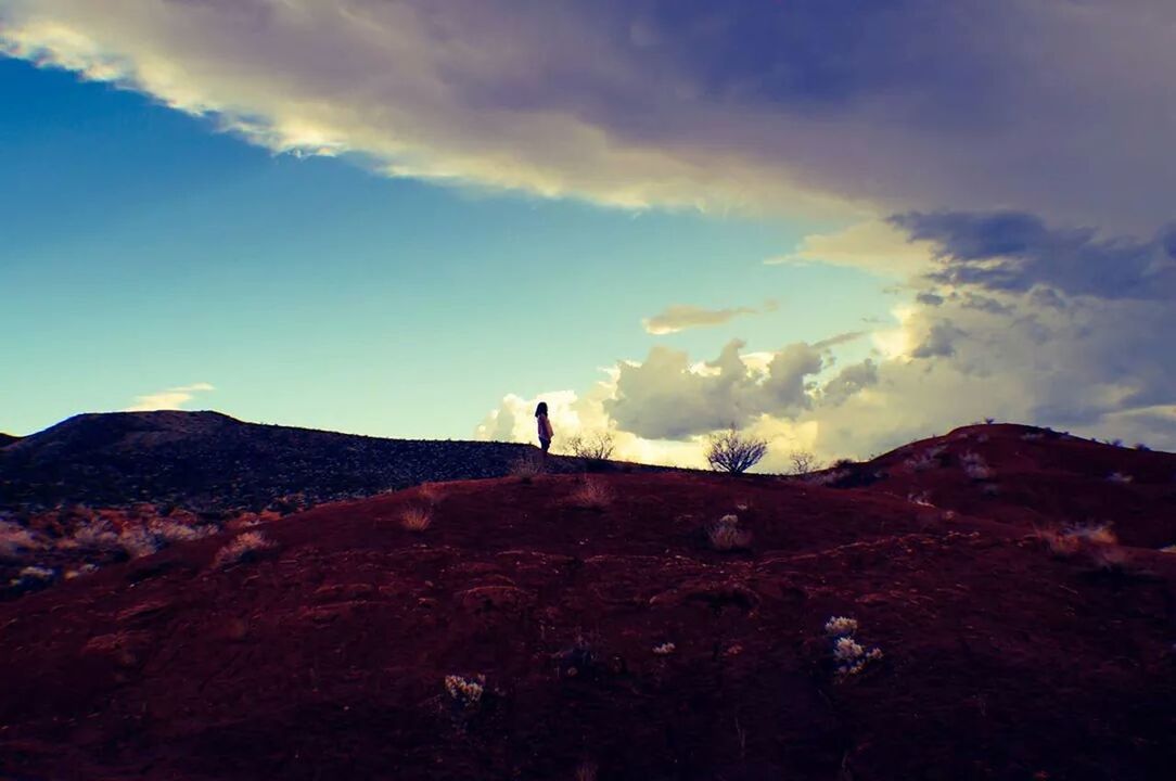 Silhouette view of women standing on hill against cloudy sky