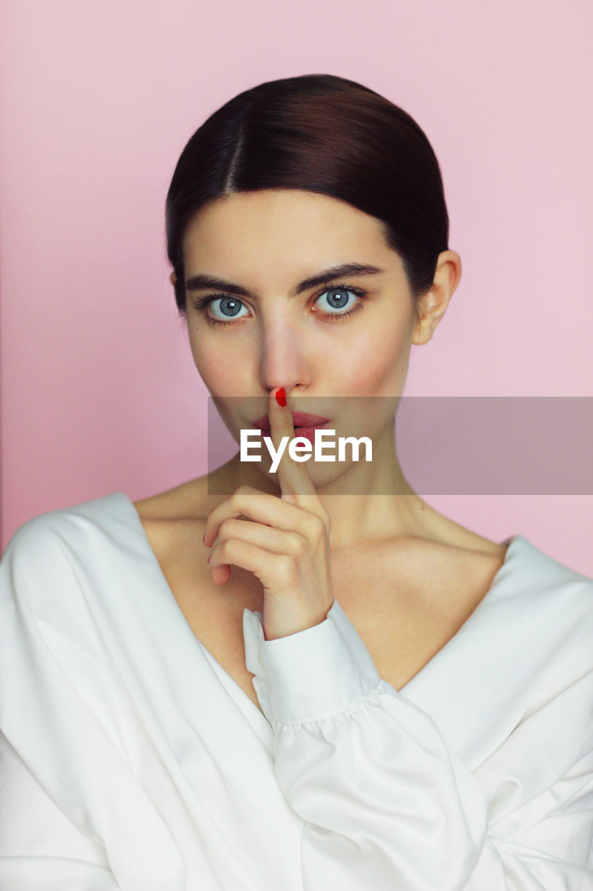 Portrait of beautiful woman against pink background