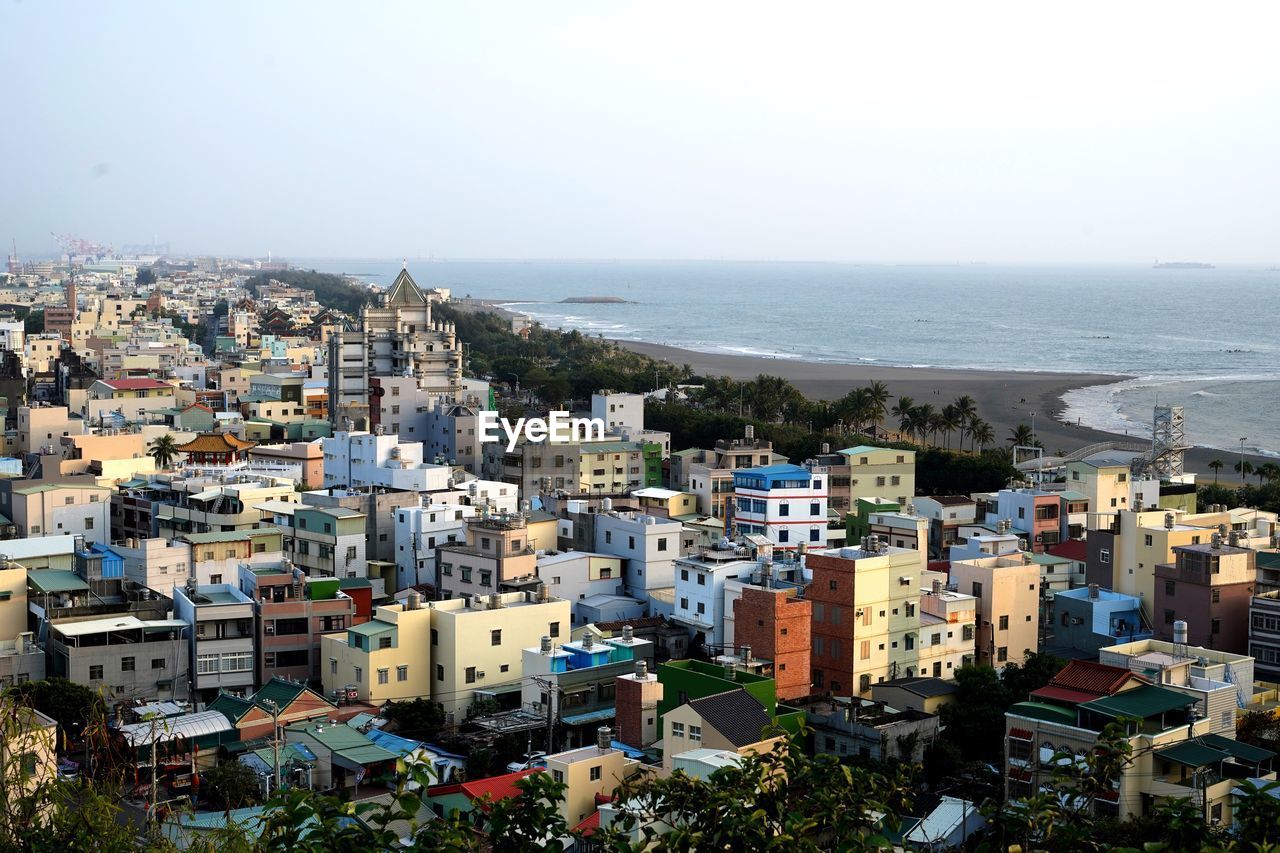 High angle view of townscape by sea against clear sky