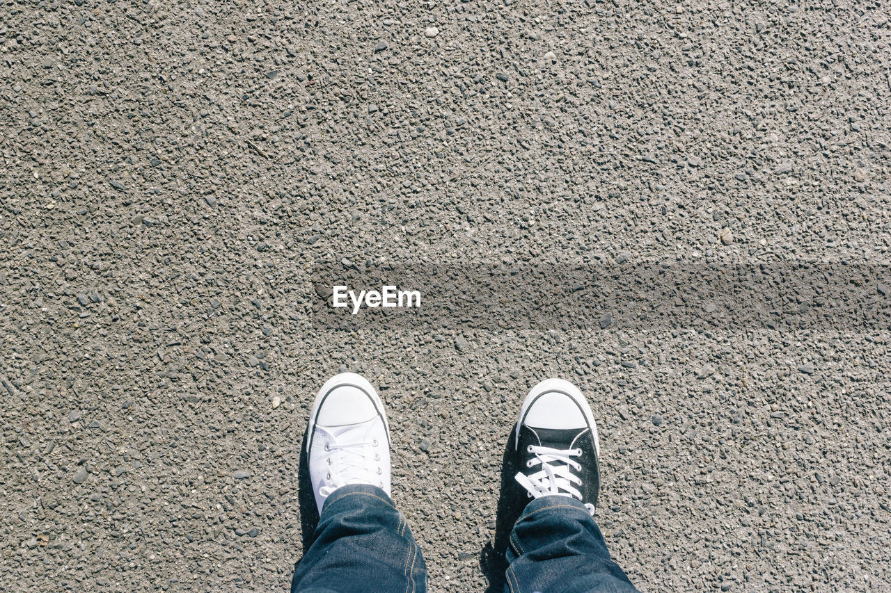 Low section of man wearing different shoes on street