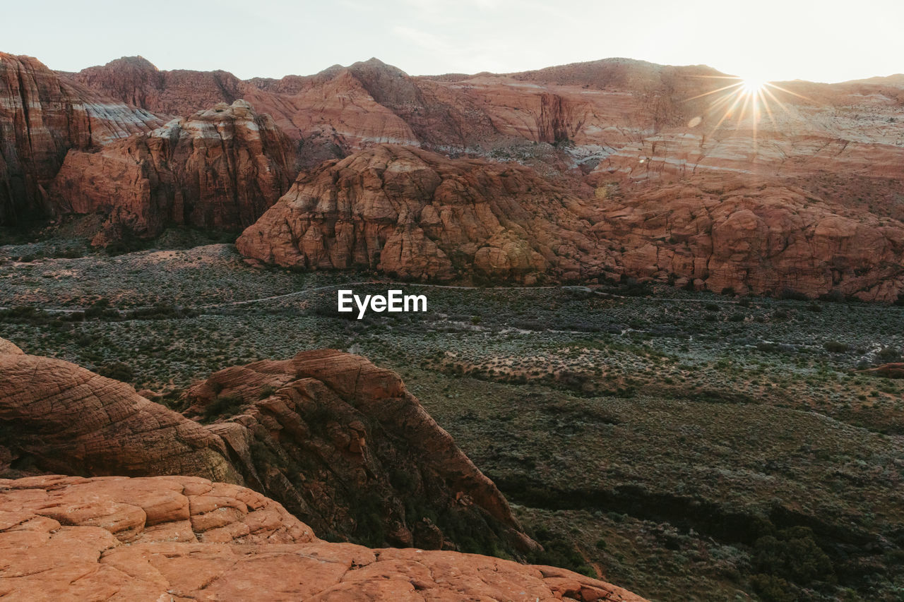 Sun sets on red cliffs across valley at snow canyon state park