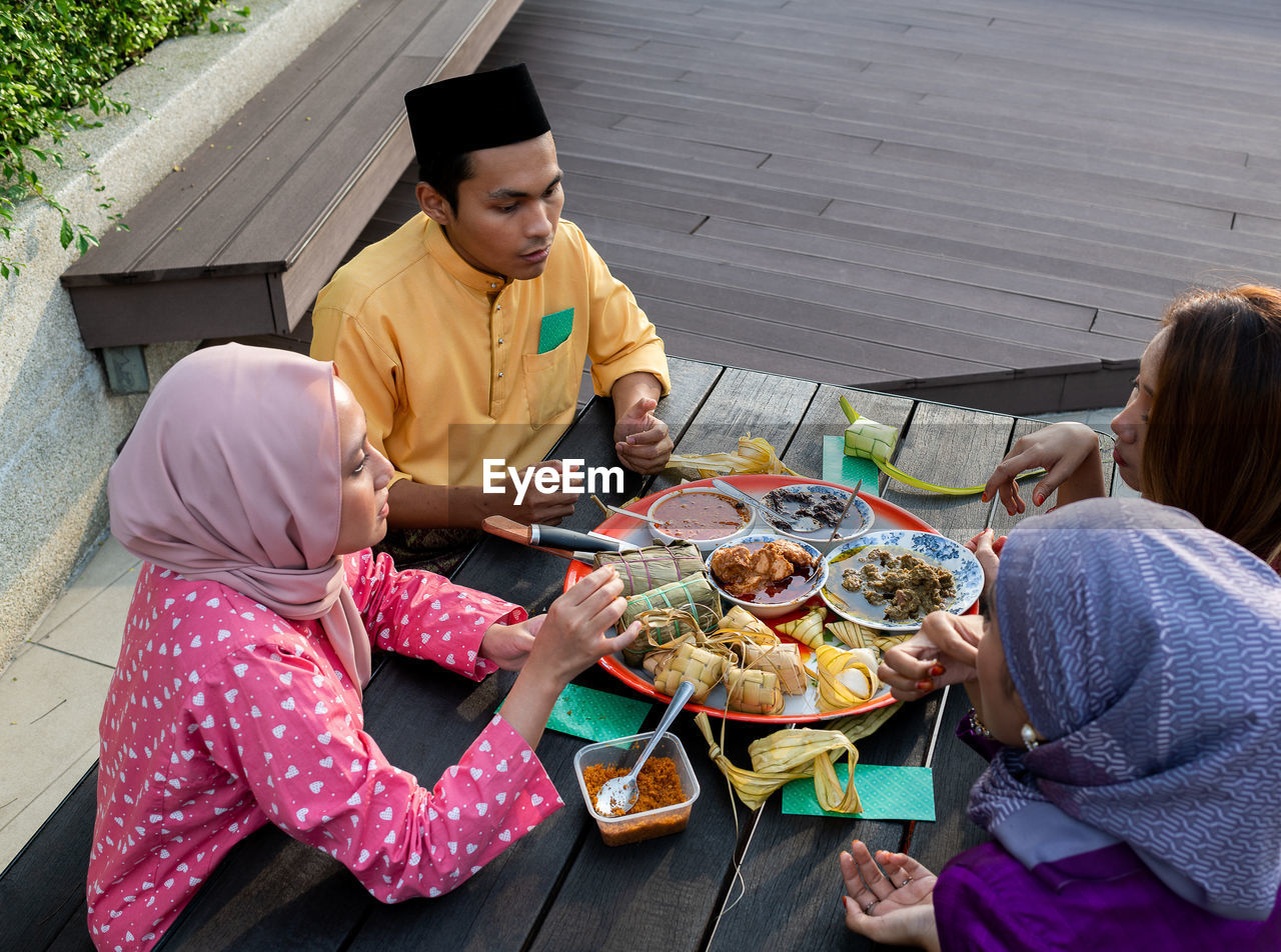 Muslim family enjoys variety of traditional cuisines on circular tray on black table, end of ramadan