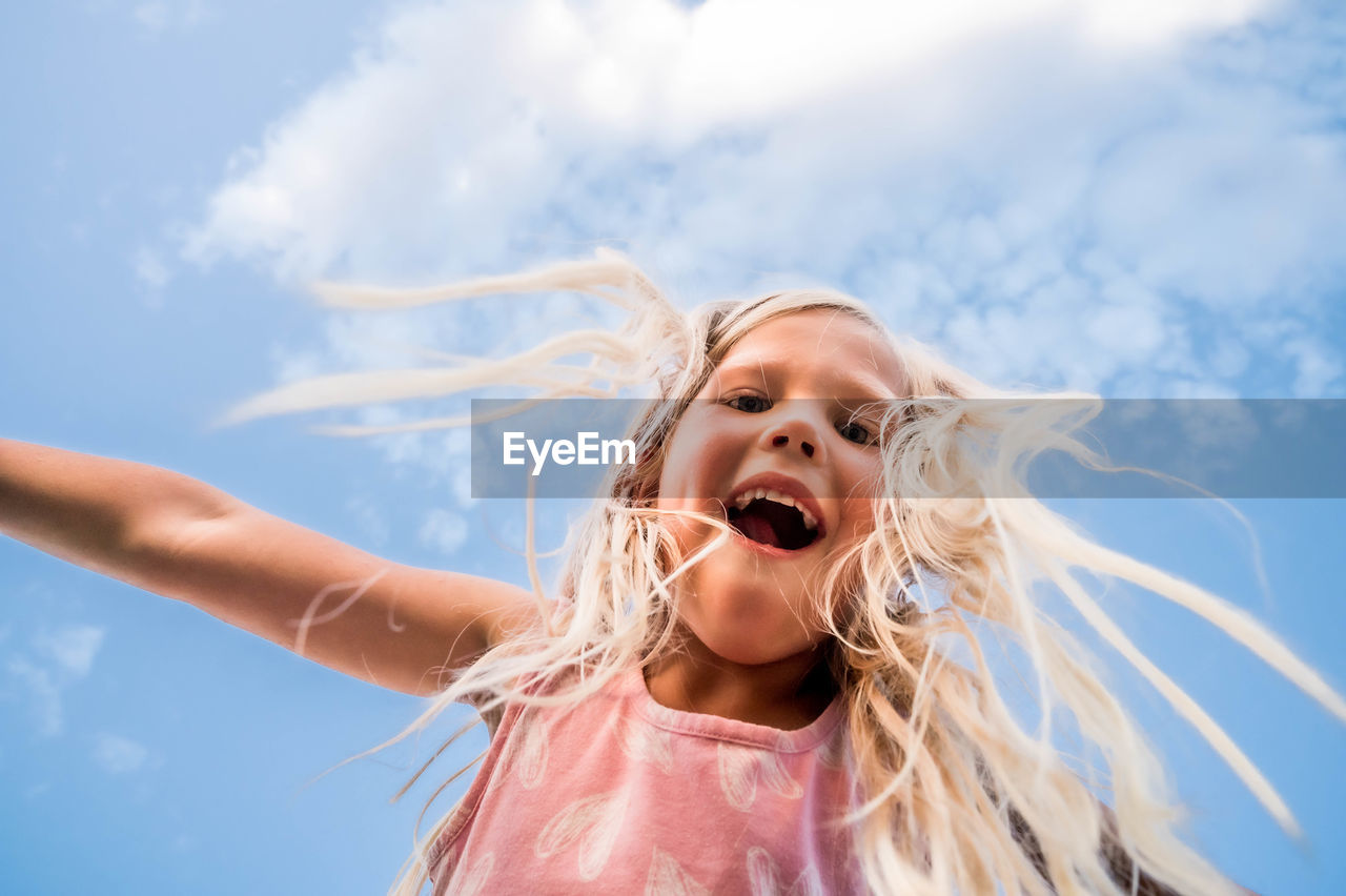 Blonde girl looking down with a blue sky background