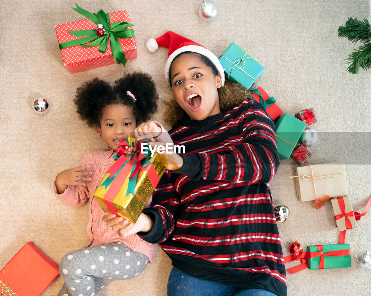 Directly above shot of cheerful mother and daughter lying by gift boxes on floor
