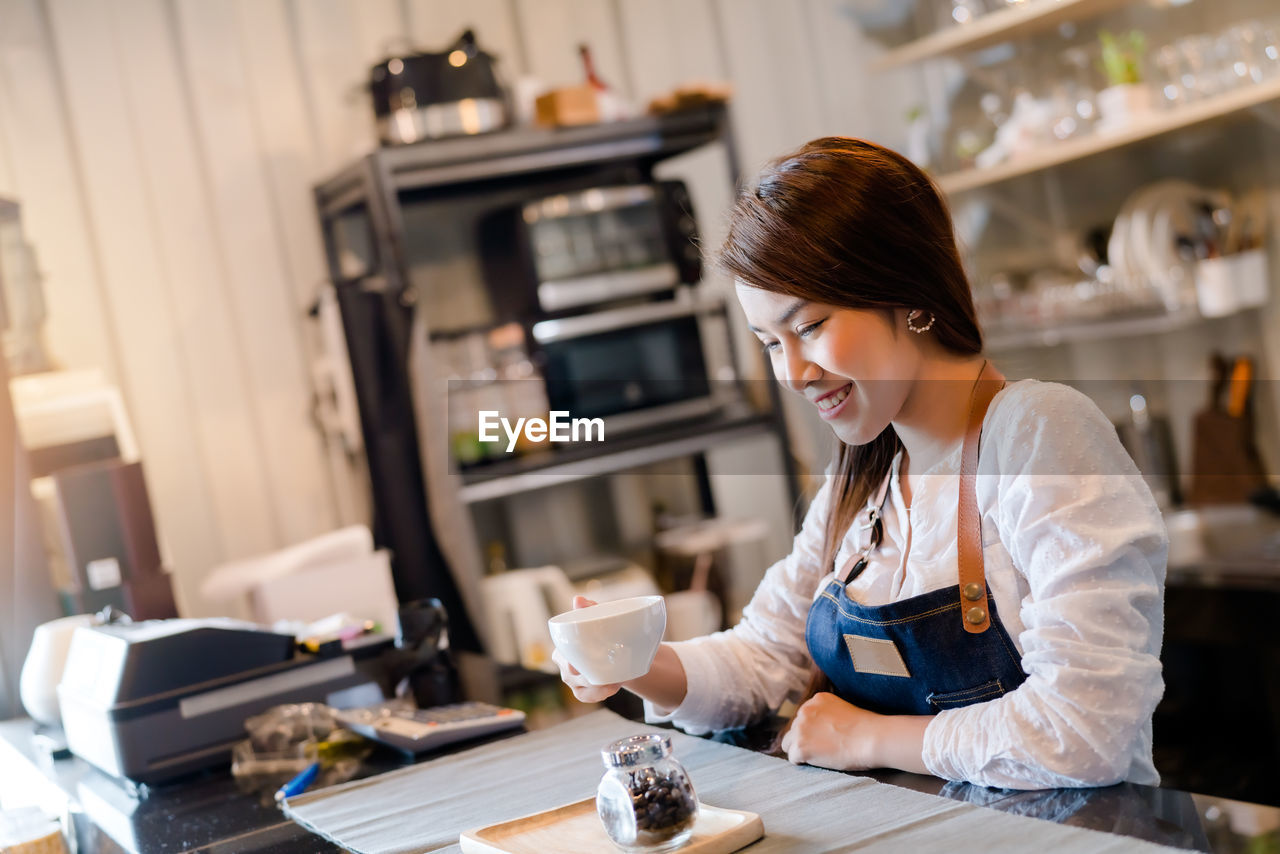 YOUNG WOMAN USING SMART PHONE IN CAFE