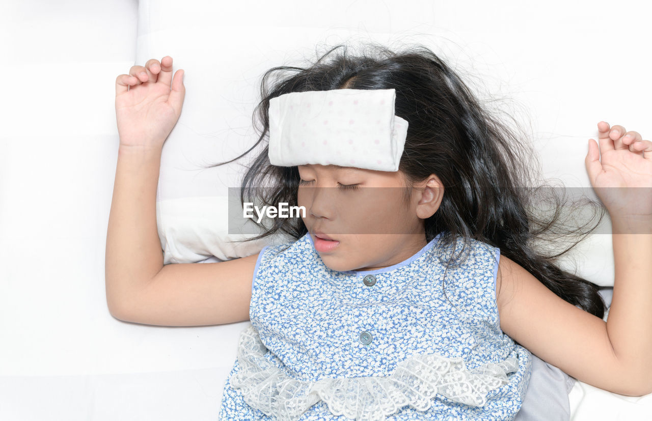 Sick child with high fever laying in bed. compress on forehead. health care concept