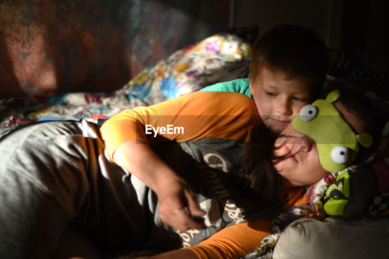 Mother and son lying on bed at home