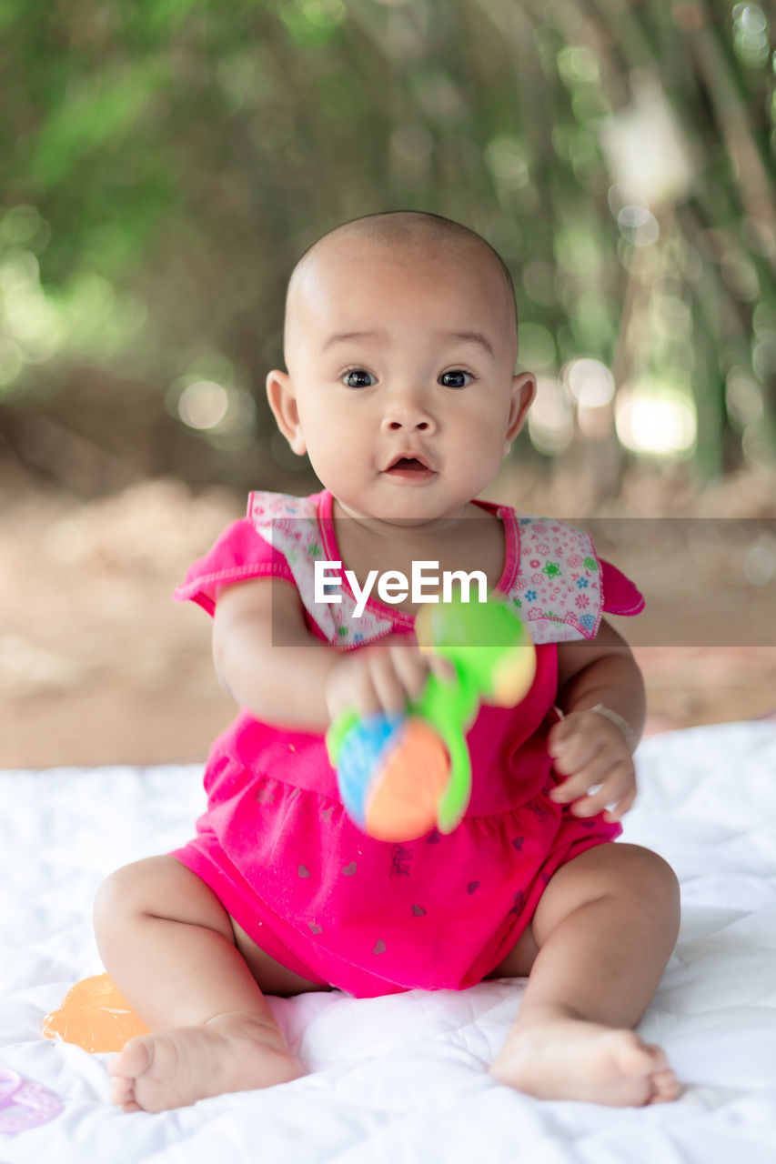 Portrait of cute baby girl sitting on bed