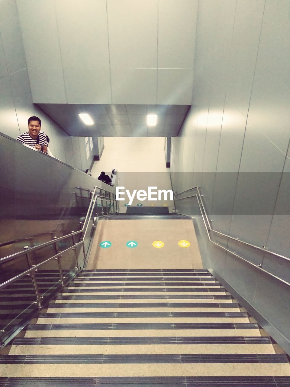 HIGH ANGLE VIEW OF WOMAN WALKING ON ILLUMINATED STAIRCASE