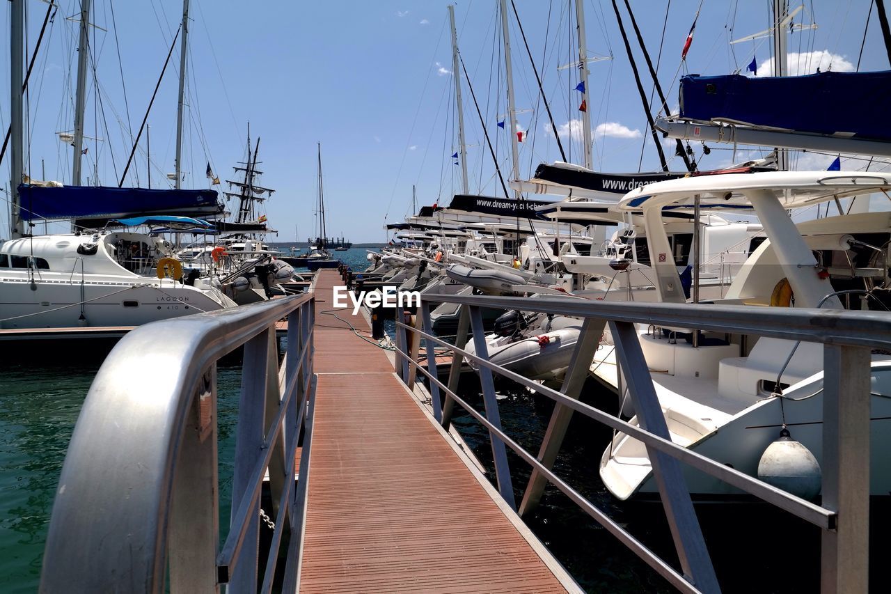 Empty pier amidst yachts moored at harbor