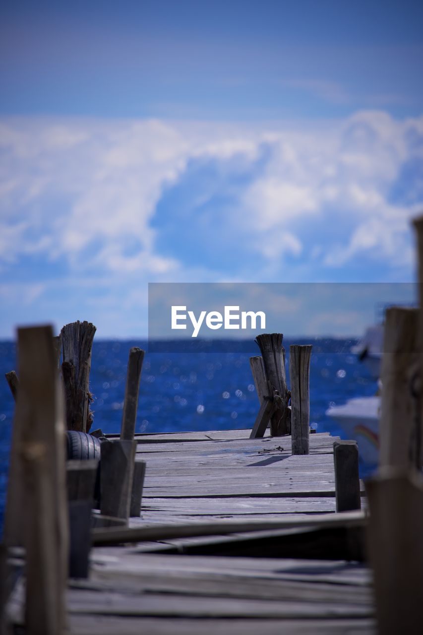 blue, sky, cloud, ocean, sea, wood, reflection, water, nature, no people, sunlight, coast, tranquility, horizon, day, morning, pier, outdoors, tranquil scene, scenics - nature, beauty in nature, post, land, architecture, beach, wooden post, selective focus