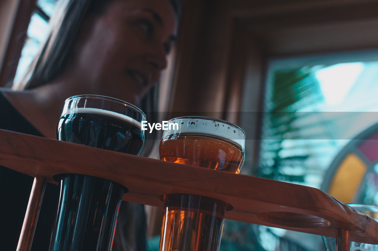 Low angle view of craft beer with woman in background at bar