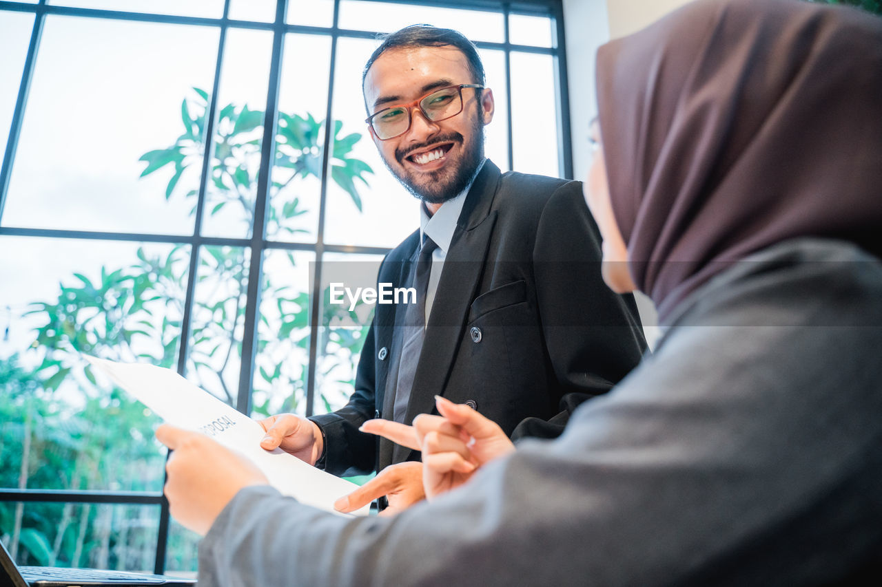 low angle view of businessman using mobile phone while standing in office