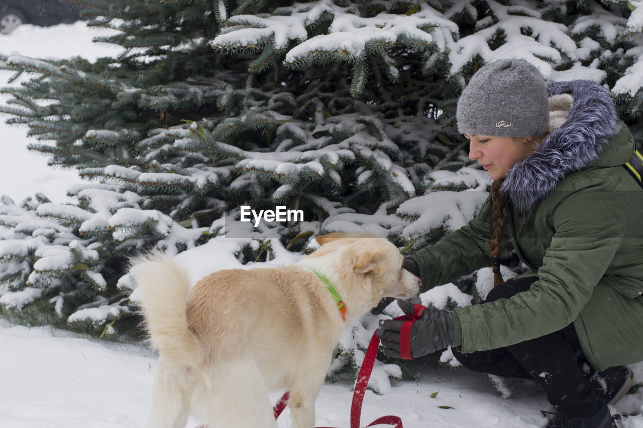 Girl with dog in front of snow covered tree
