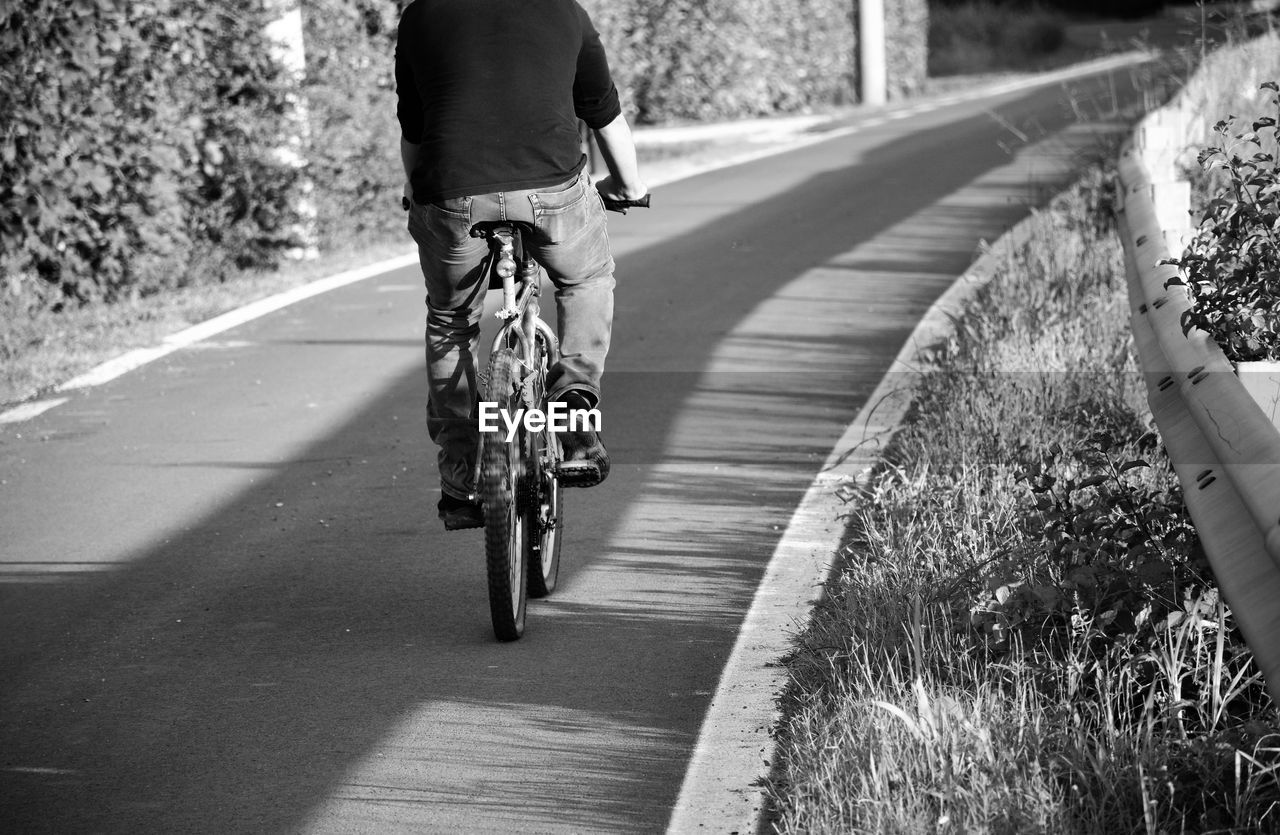 Rear view of man riding bicycle on road