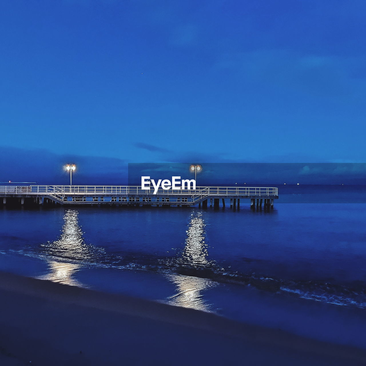 VIEW OF ILLUMINATED BEACH AGAINST BLUE SKY