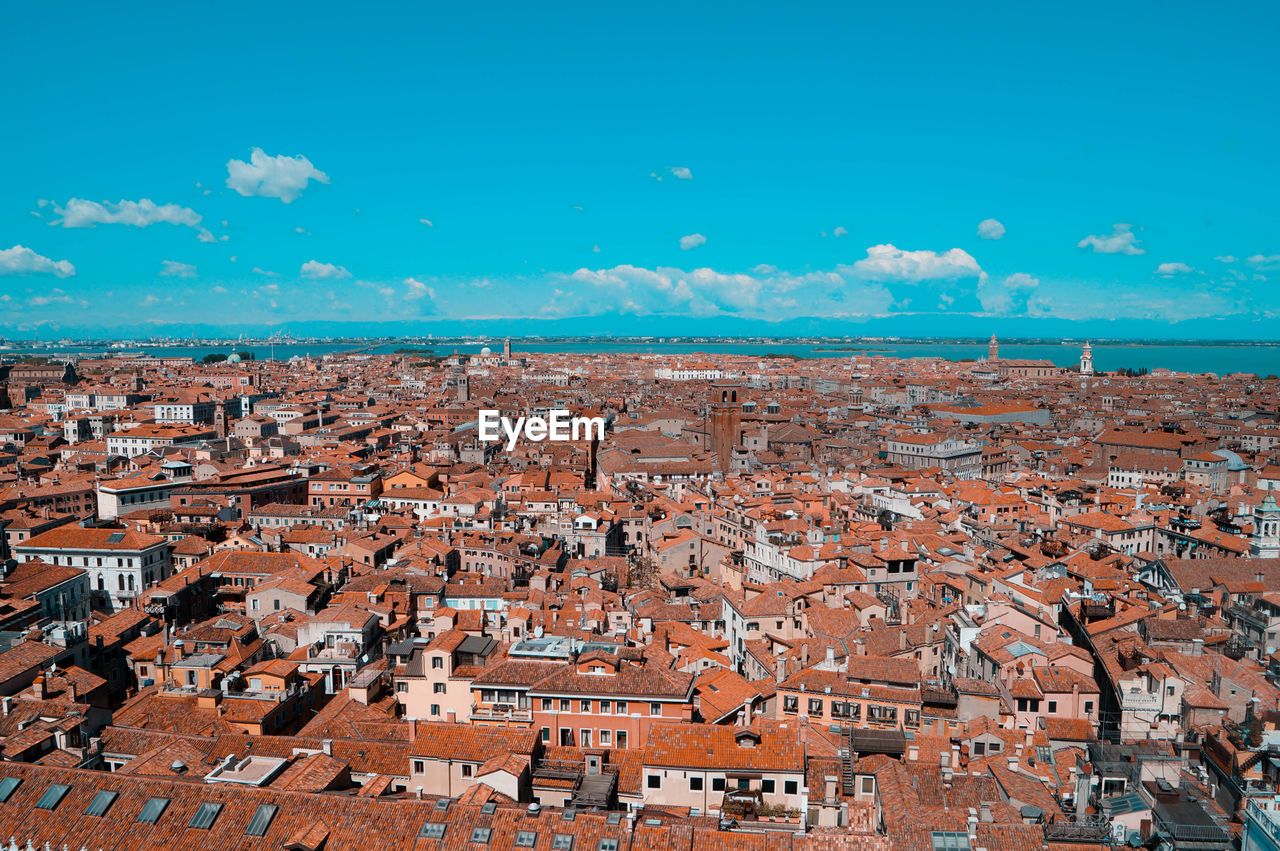 Aerial view of town by sea against blue sky