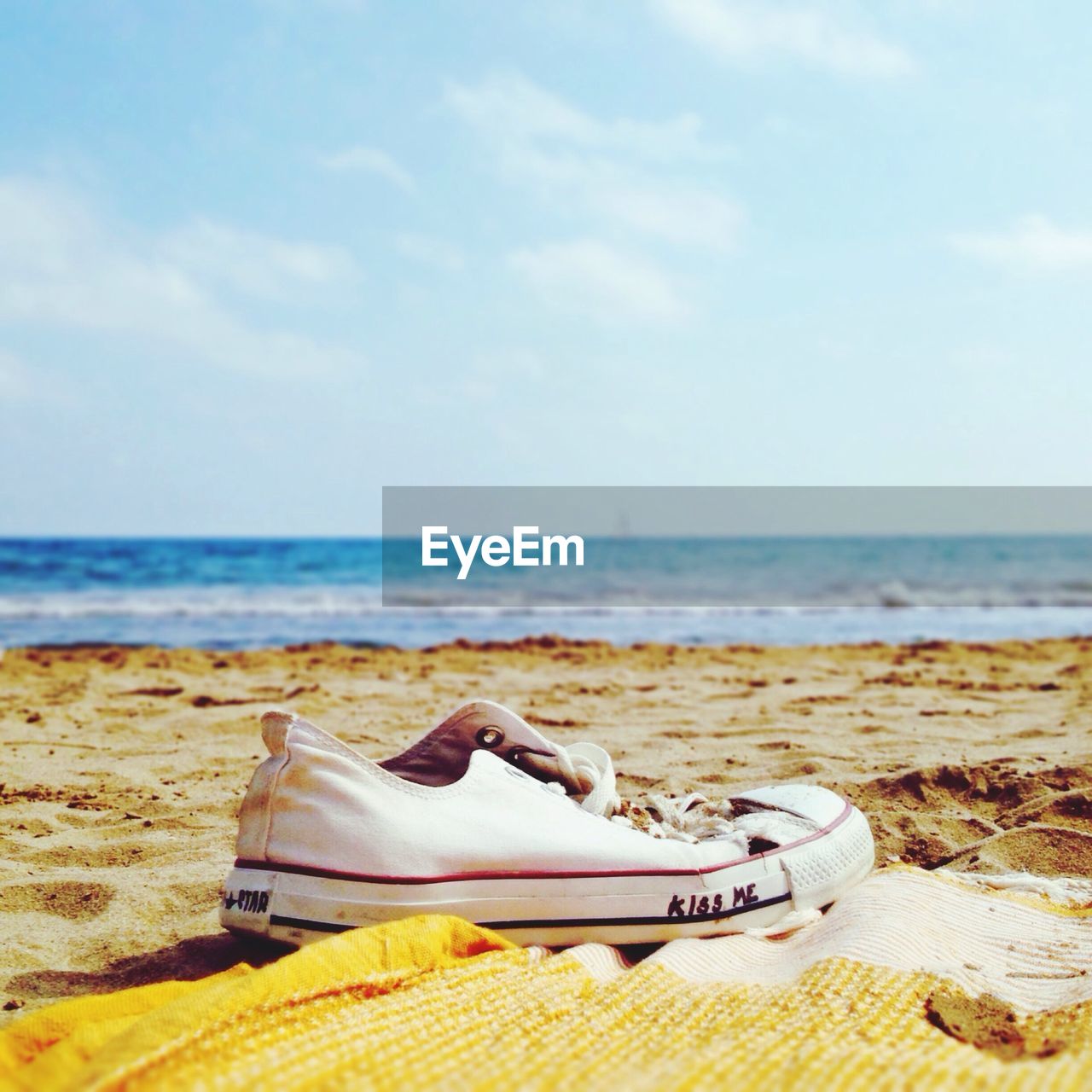 Canvas shoe at beach against sky