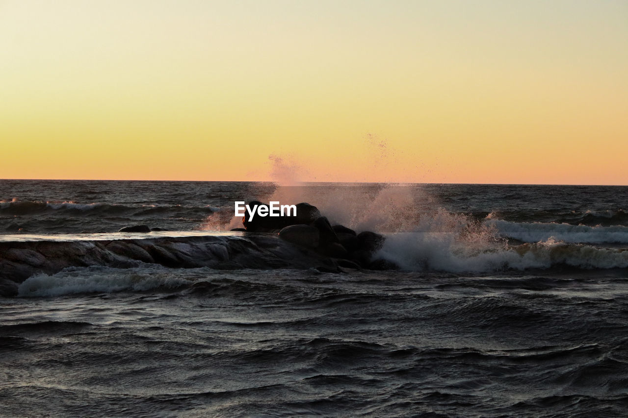 WAVES BREAKING AGAINST SEA DURING SUNSET