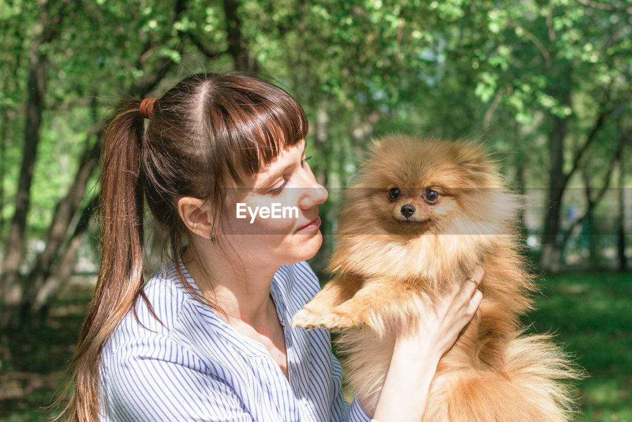 Portrait of young caucasian woman with puppy of pomeranian spitz. friendship between person and dog.