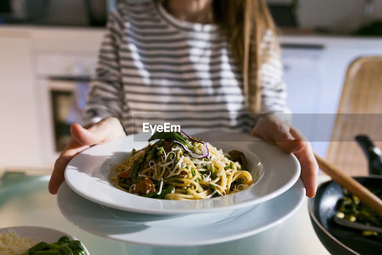 Young woman serving vegan pasta dish