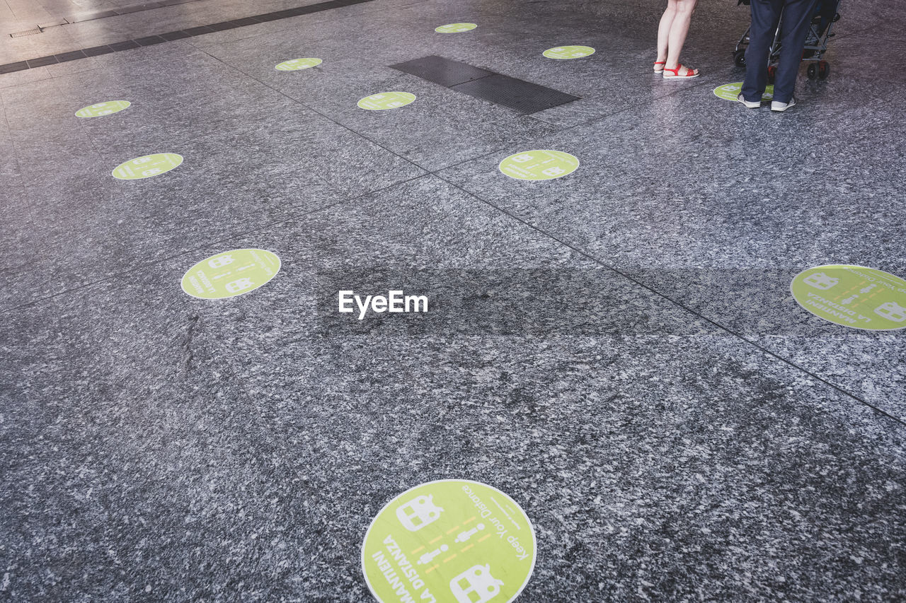 LOW SECTION OF WOMAN STANDING ON YELLOW ROAD