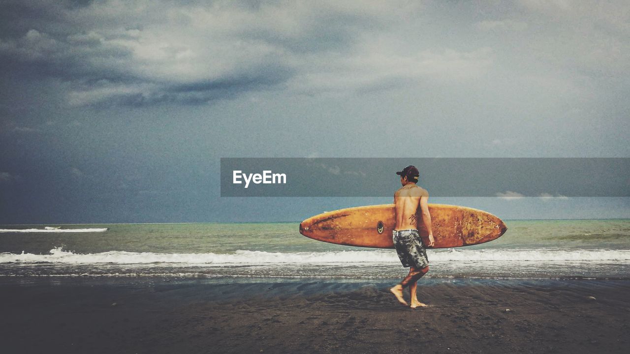 FULL LENGTH REAR VIEW OF MAN ON BEACH