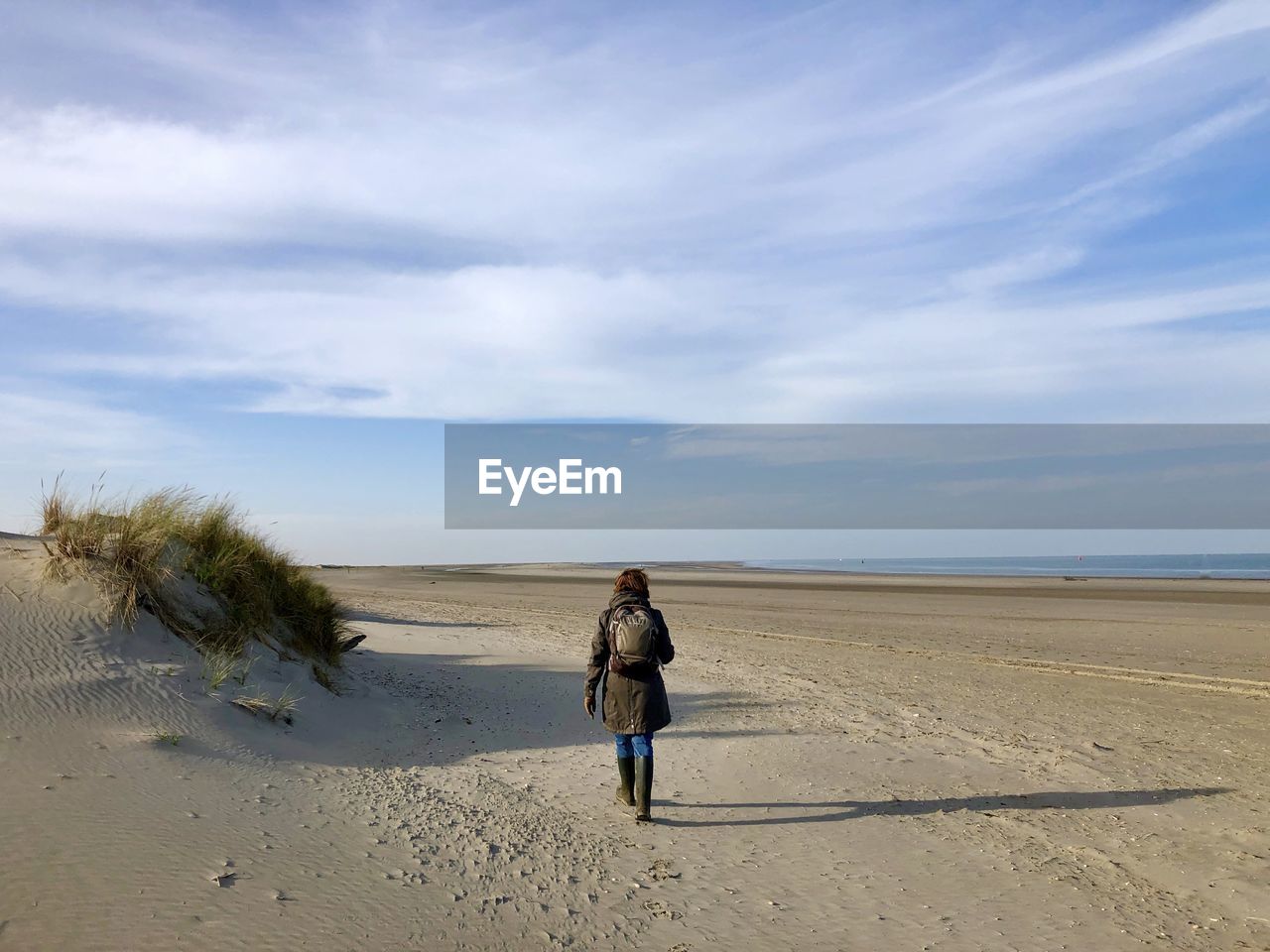 Rear view of woman on beach against sky