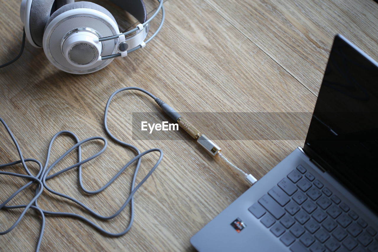 high angle view of in-ear headphones and laptop on table