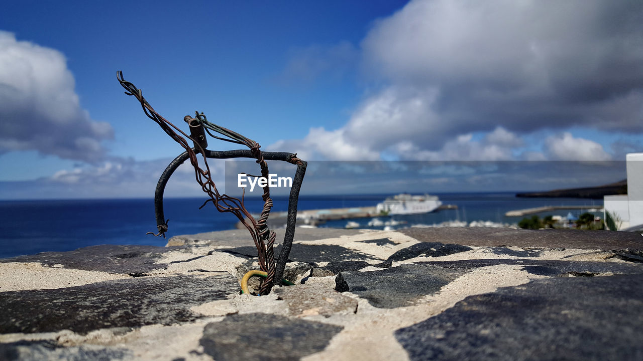 Abandoned cables at rocky beach against sky