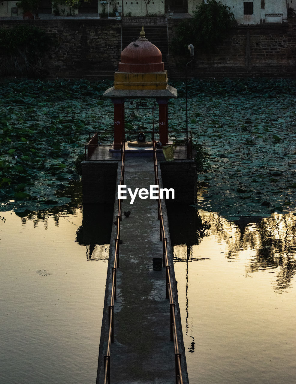 A hindu small temple with shivling on a lake, pier on lake.