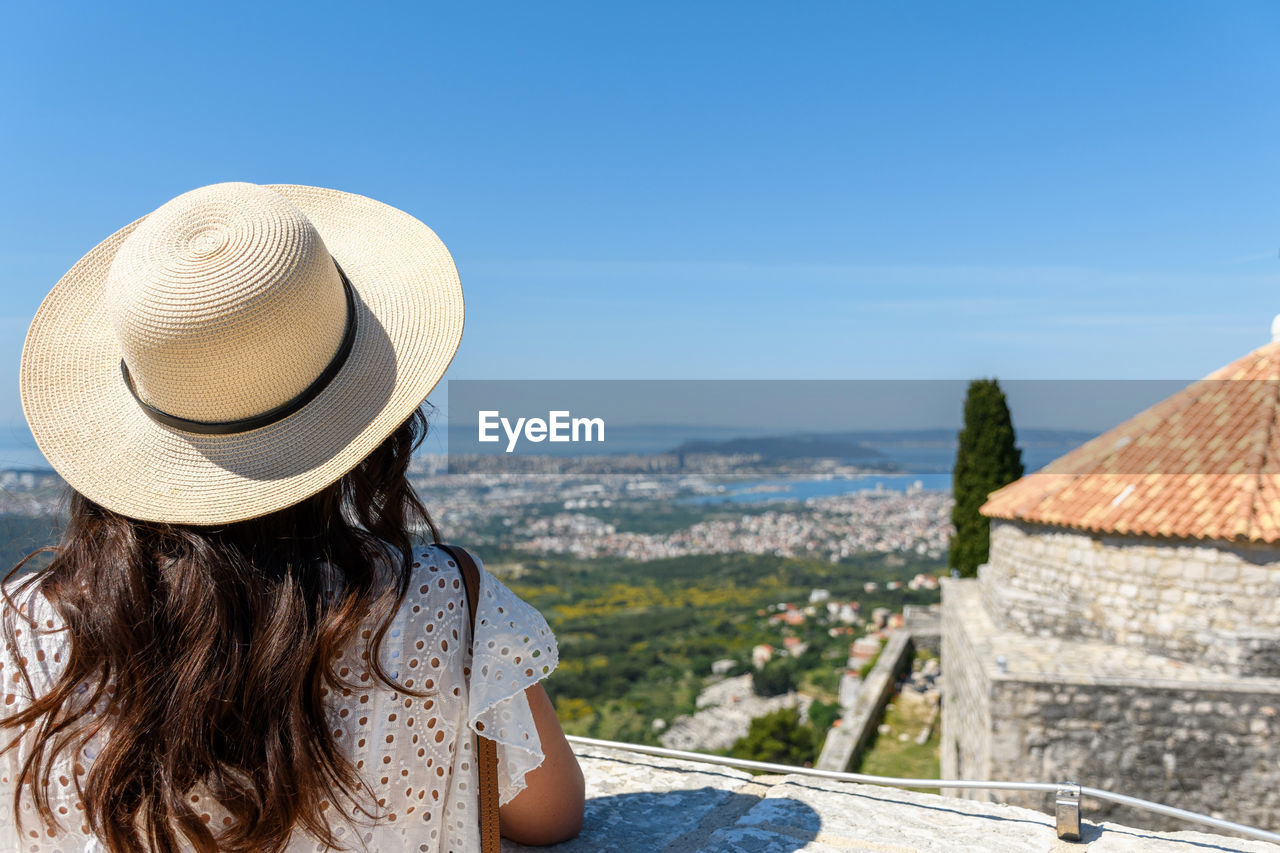 Rear view of woman standing on hill at klis fortress above city of split in croatia